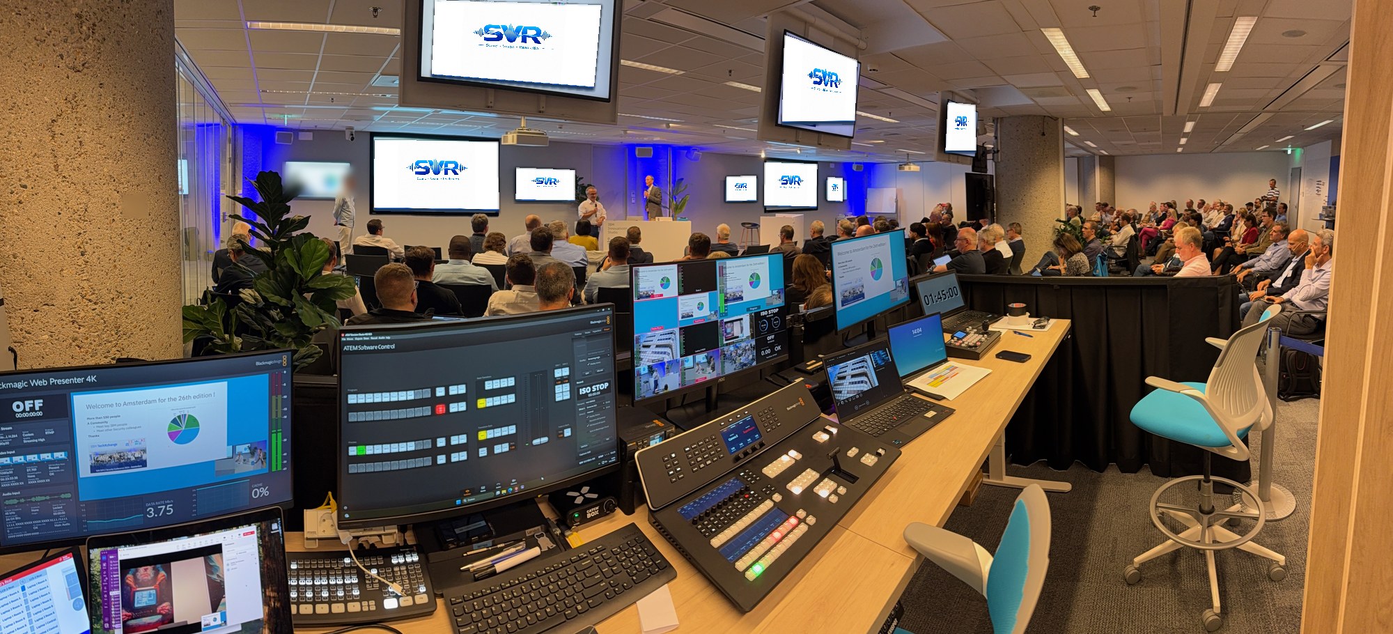 Panoramisch overzicht van regie achter de schermen tijdens conferentie